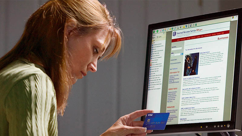 Woman using a computer and looking at credit card