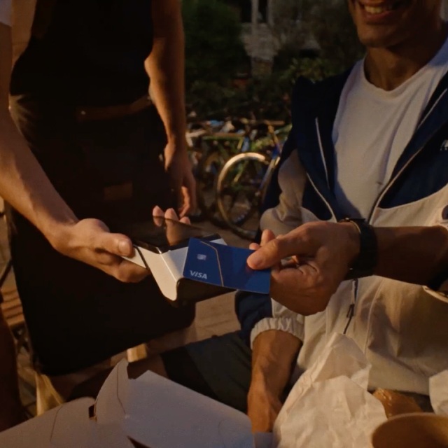 Person using a Visa card to make a payment with a card reader outdoors