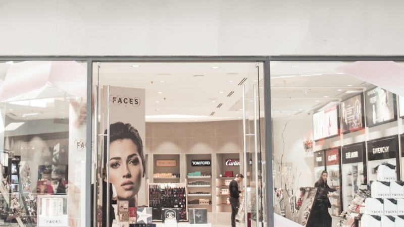 Storefront of a cosmetics shop with glass doors and displays of luxury brands like Tom Ford and Cartier. 